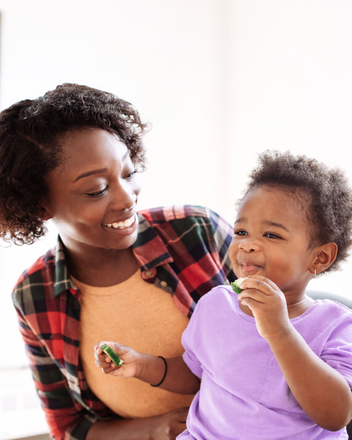 Mother Smiling Toddler Eating Cucumber