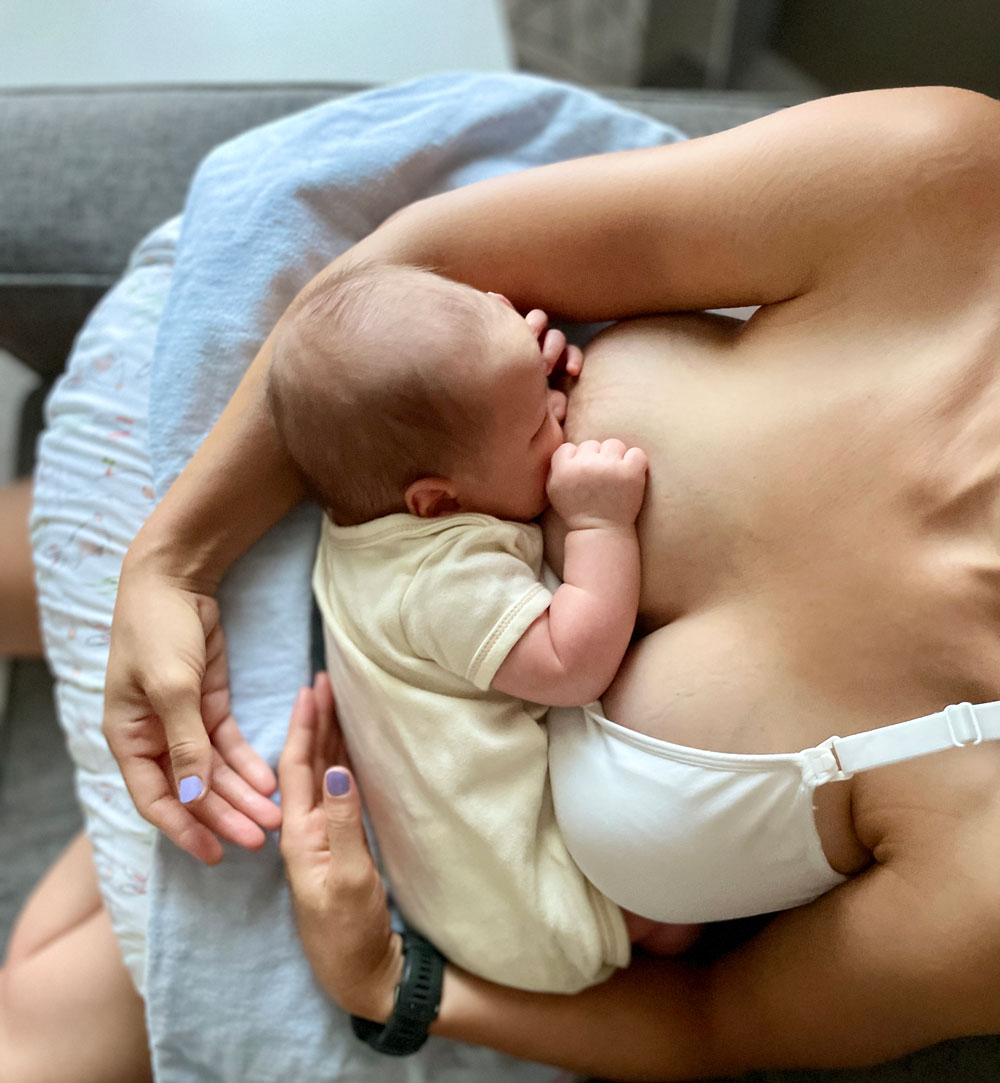 Mother breastfeeding newborn baby on couch