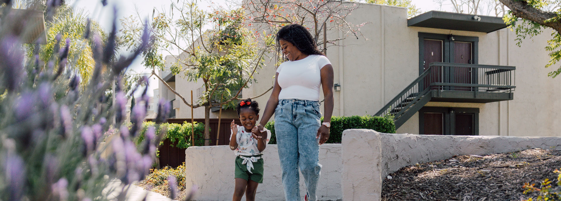 Mother and child walking outside by apartment building