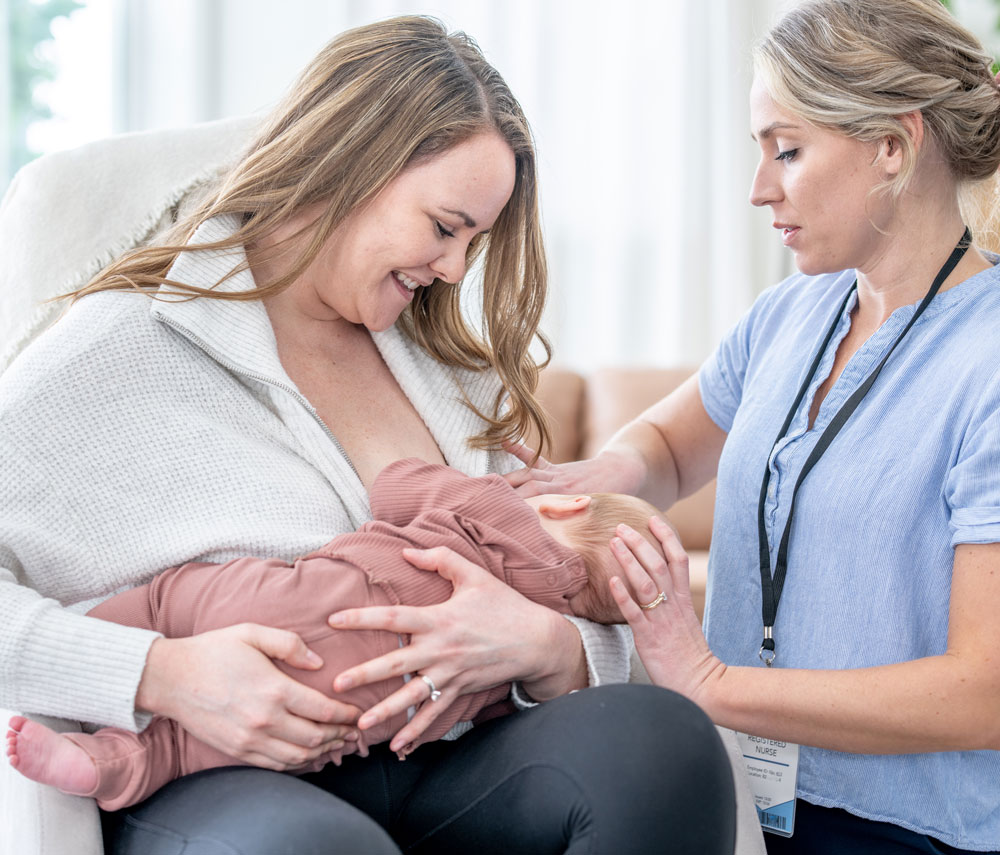 Nurse supporting mother breastfeeding baby